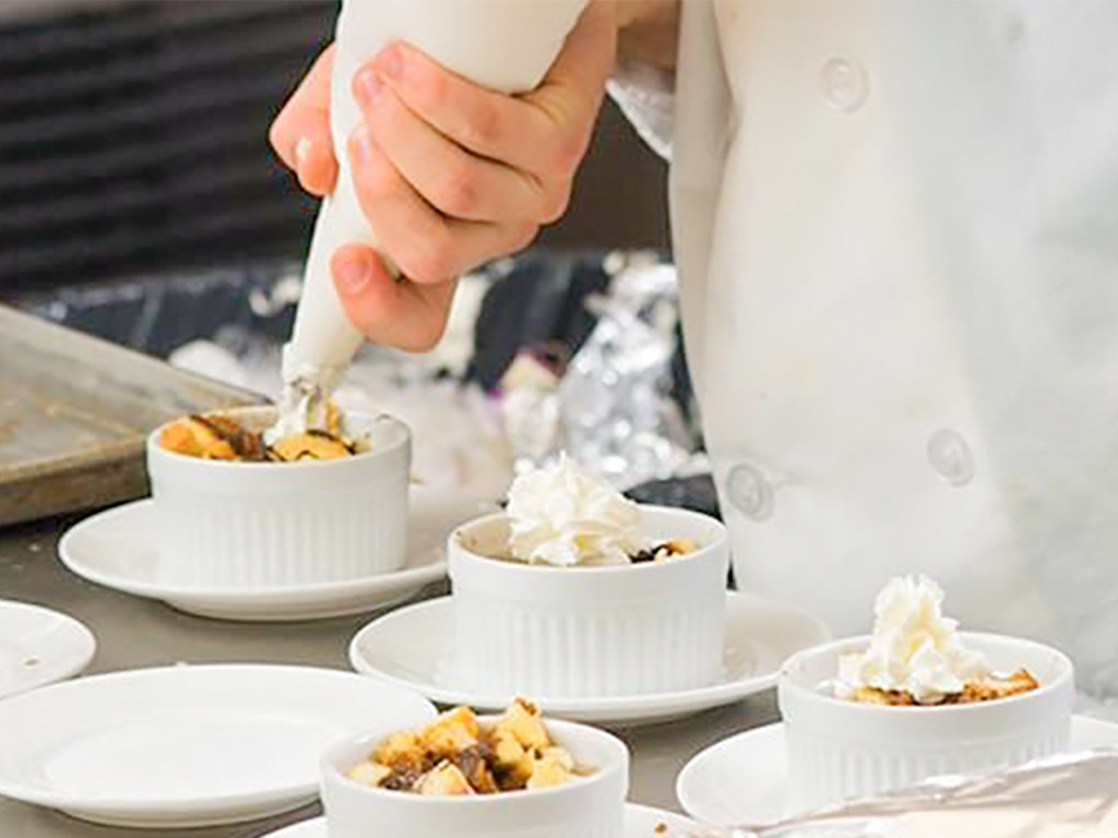 Student applying dessert piping.