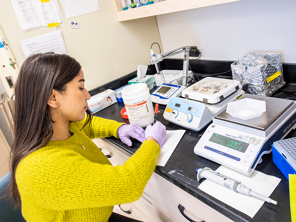 Student measuring with analytical equipment in lab.