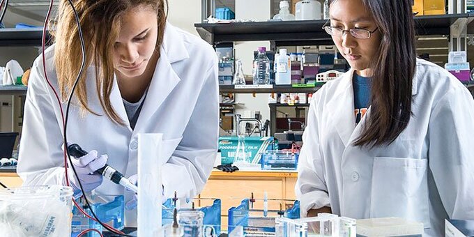 Two students working in a lab with a pipet