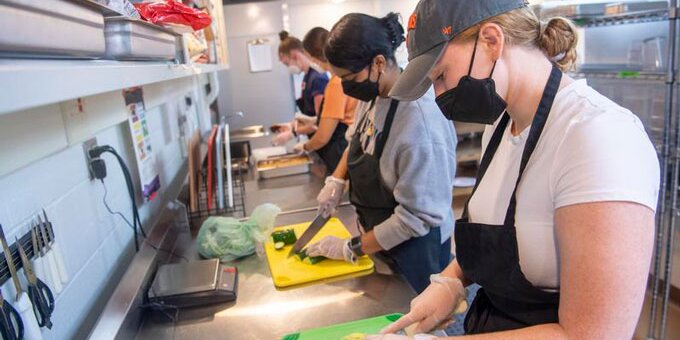Students cutting vegetables in a kitchen
