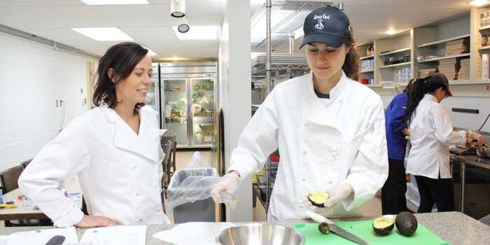 Students cut avacadoes in kitchen.