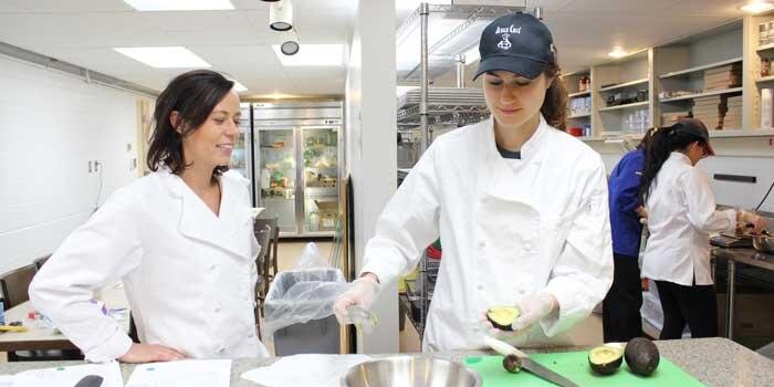 Student and professor preparing food in kitchen.