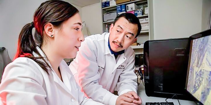 Student and instructor in laboratory working on a computer.