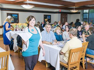 Server standing with a plate of drinks with people in the back