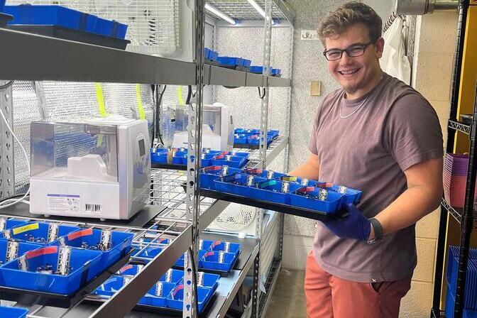 Liam Reynolds with his current microgreen trials in growth chambers.